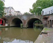843702 Gezicht op de Bakkerbrug over de Oudegracht te Utrecht, vanaf de werf aan de westzijde van de gracht, voor de ...